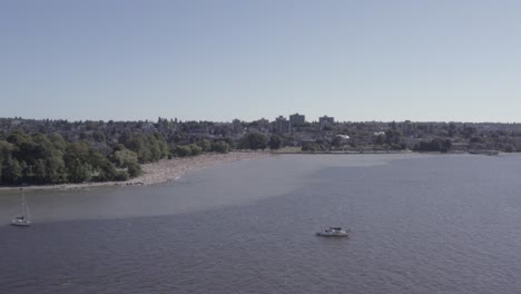 Aerial-fly-over-from-English-Bay-to-Kitsilano-Beach-on-a-hot-summer-day-as-boaters-relax-suntan-liesure-beach-activity-motor-boats-zip-by-sails-partying-romantic-fun-fishing-at-the-tropical-ocean-7-7