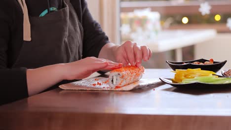 making sushi at home kitchen. woman hands rolling homemade sushi.