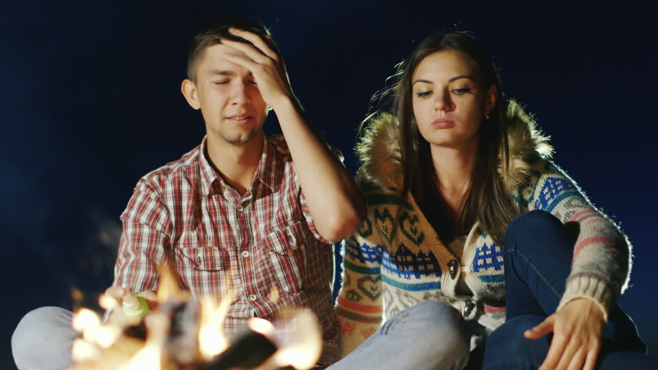 los mosquitos impiden que una pareja joven se relaje junto al fuego persiguen a los mosquitos un hombre salpica insectos re