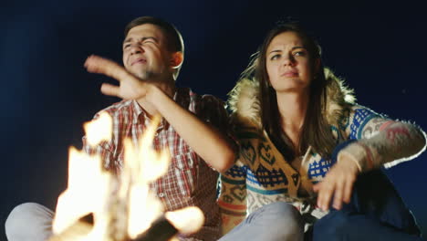 los mosquitos impiden que una pareja joven se relaje junto al fuego persiguen a los mosquitos un hombre salpica insectos re