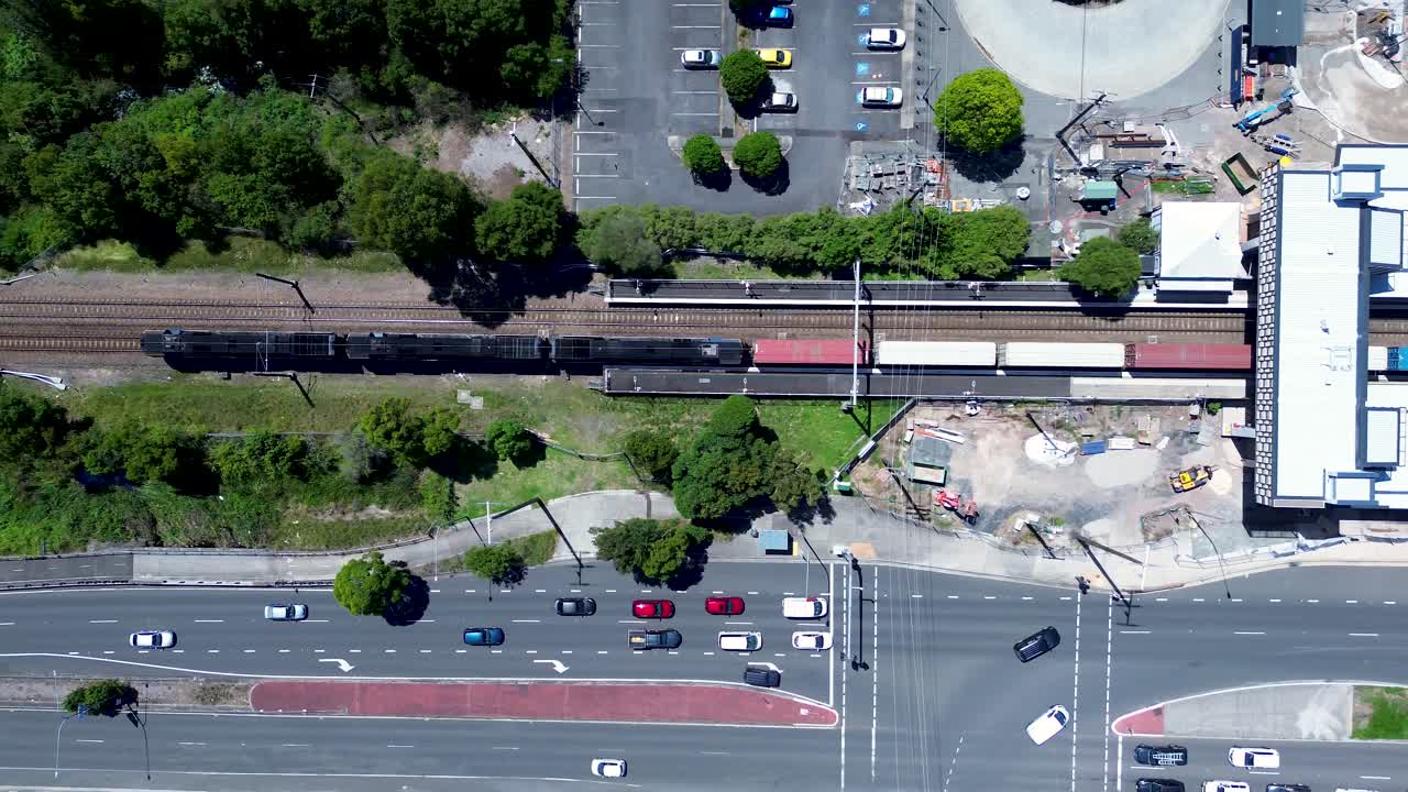 Drone aerial landscape of freight cargo train on railway tracks with car vehicles driving through intersection traffic lights at Tuggerah Central Coast Australia travel tourism urban