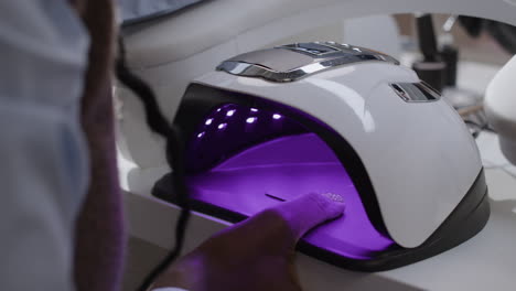 manicurist using uv lamp to cure nails