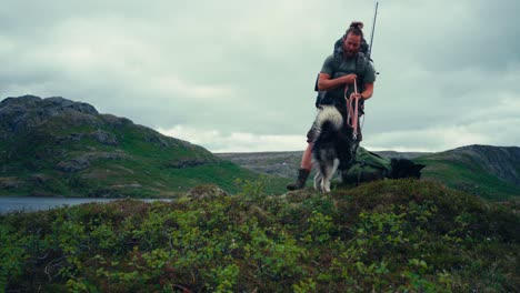 traveling tourist with alaskan malamute near shore of palvatnet lake by the mountains in osen, norway