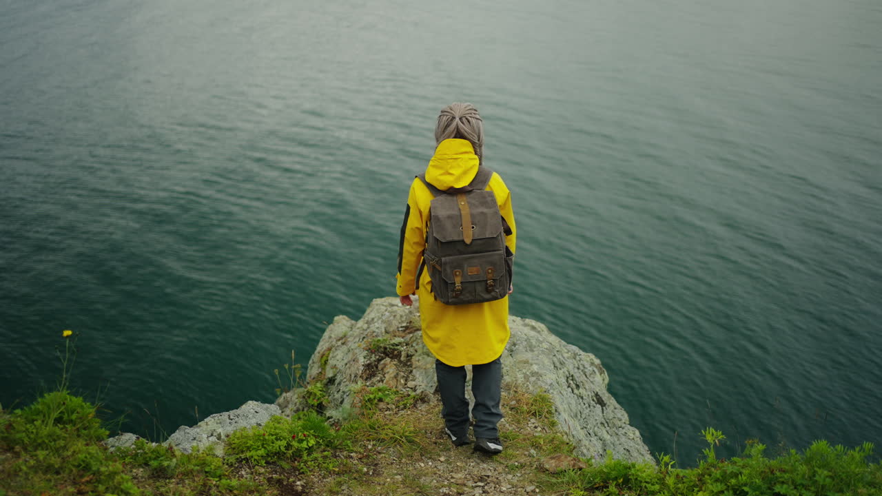 Woman Hiking on a Cliff Overlooking a Lake