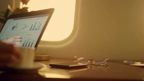 Hands-working-laptop-charts-on-private-jet-closeup.-Company-ceo-analyzing-data