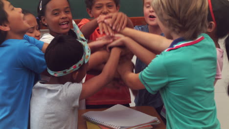 Pupils-holding-hands-together-and-cheering-in-classroom