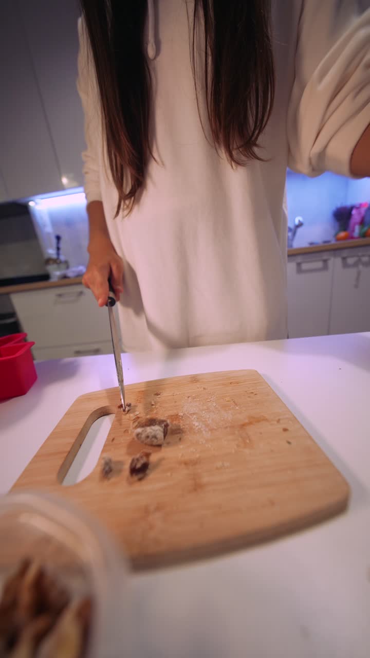 Donna che taglia frutta secca su un tagliere in una cucina moderna