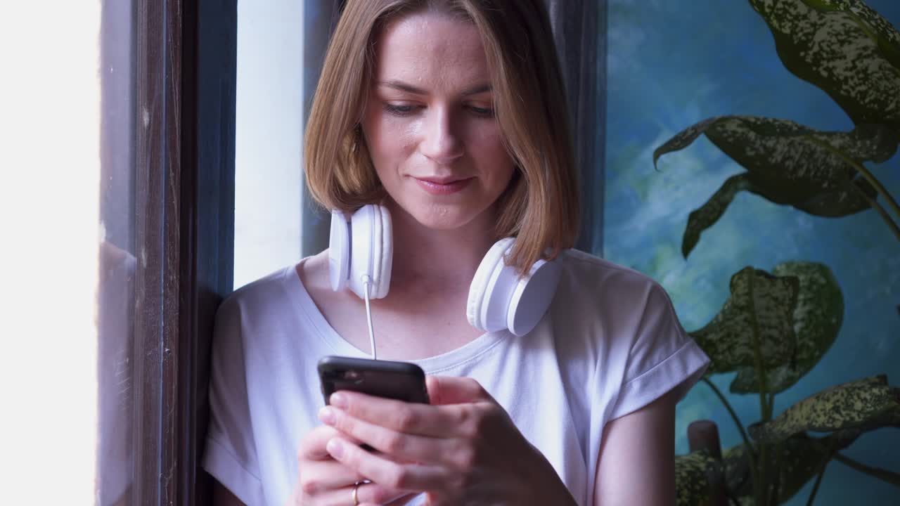 ragazza con le cuffie che guarda attraverso la finestra