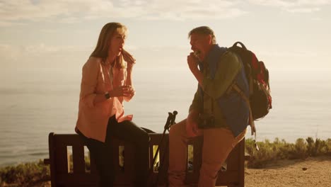 active senior couple eating and sitting on bench in forest