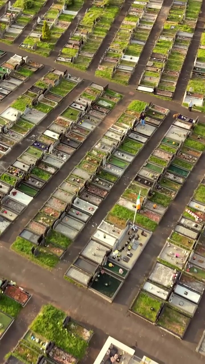 60FPS overhead vertical social ratio aerial video of Milltown Cemetary and the Republican Plot in West Belfast, Northern Ireland in the UK on a bright sunny day. Produced with Rec709 colour.