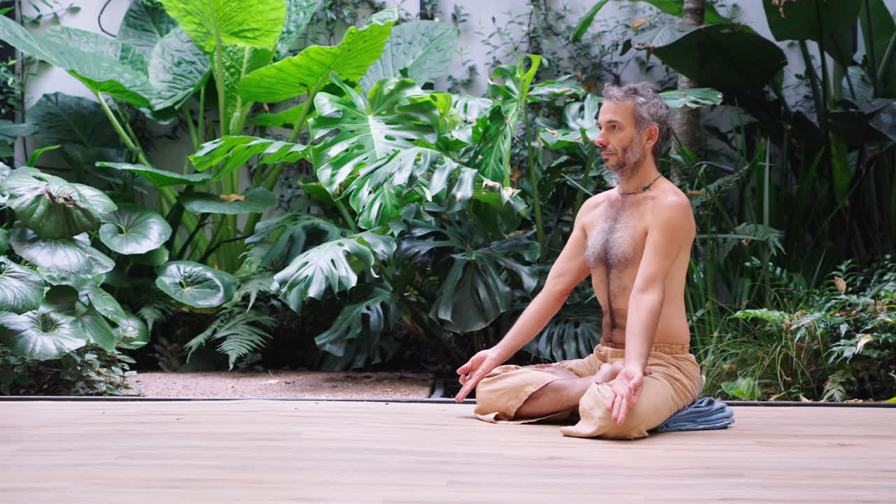 Hombre meditando en posición de loto junto a un jardín verde y exuberante