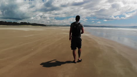 retrospectiva de un mochilero con sombrero en la playa de dunas de arena de porangahau en la isla norte de nueva zelanda