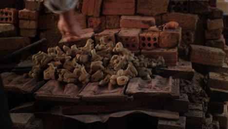 A-close-up-of-a-man-stacking-newly-crafted-animal-flutes-in-Thanh-Ha-pottery-village,-Vietnam,-showcasing-the-traditional-pottery-artistry-and-tourism