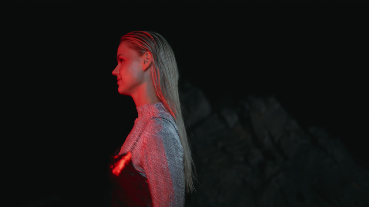 modelo de moda caminando por la noche en la costa rocosa de primer plano.