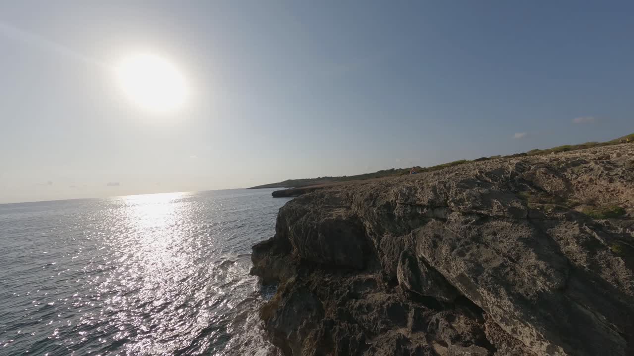 fpv vuelo a lo largo de escarpados acantilados de piedra caliza océano sol