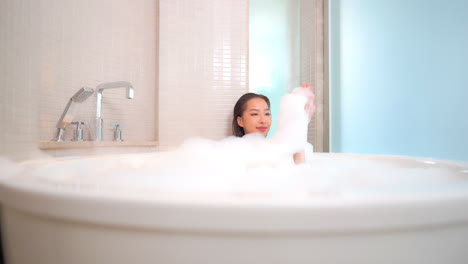 An-attractive-young-woman-up-to-her-neck-and-completely-covered-in-bubbles-is-taking-a-bath