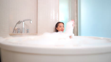 an attractive young woman up to her neck and completely covered in bubbles is taking a bath