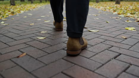 Close-up-feet-walking-along-path-in-autumn-park-in-day-time.-Man-legs-in-park