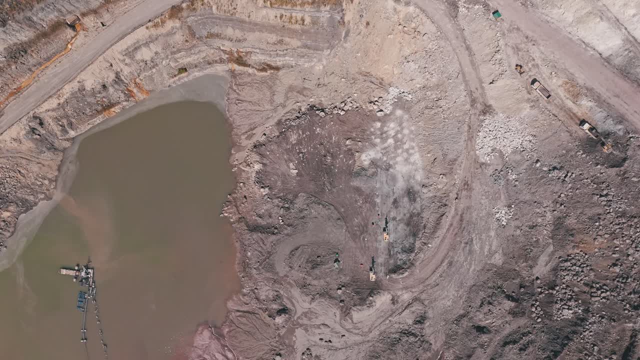 An aerial drone shot of a brown murky lake at the bottom of quarry in Siana Gold and Silver Mine, Mainit, Philippines