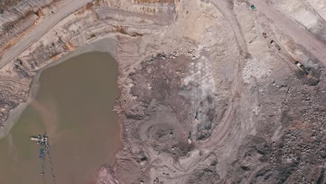 an aerial drone shot of a brown murky lake at the bottom of quarry in siana gold and silver mine, mainit, philippines