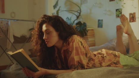 young woman lying on bed, reading book in sunlit room during day at home