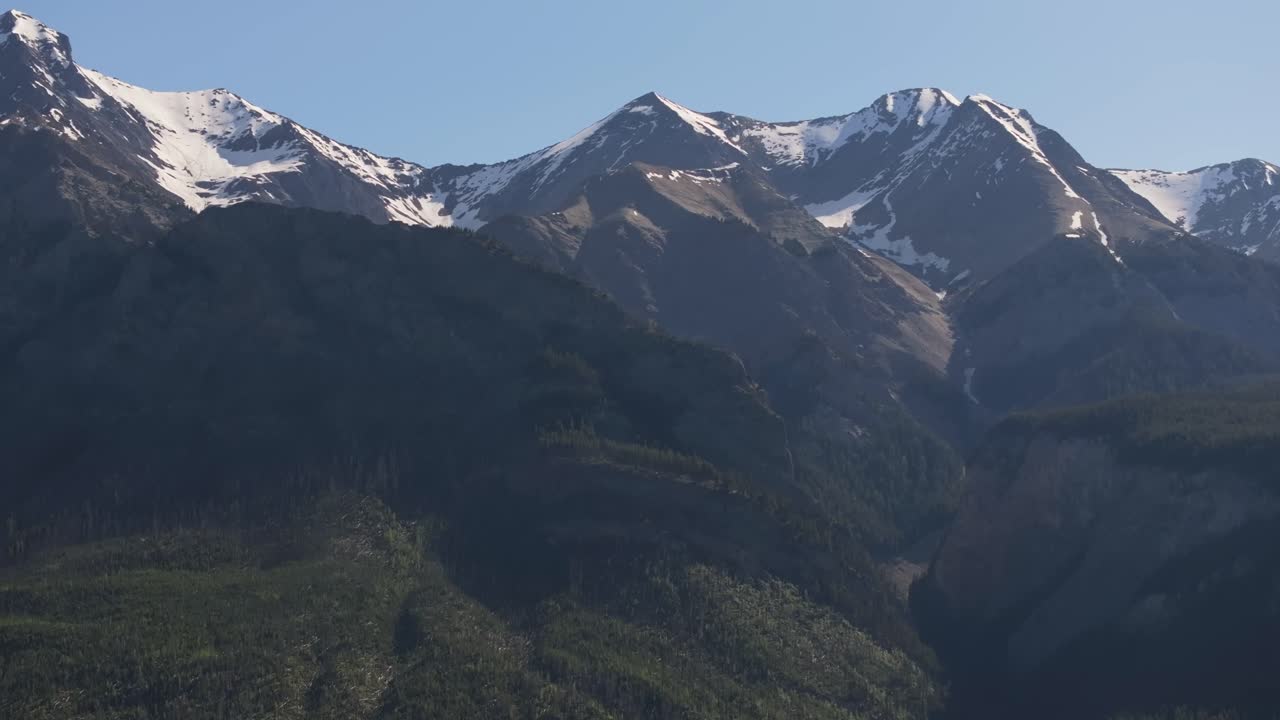 drone ampliado revelando enormes montañas nevadas y un vasto bosque de pinos salvaje cerca de banff y yoho national park en canadá bajo un cielo parcialmente nublado