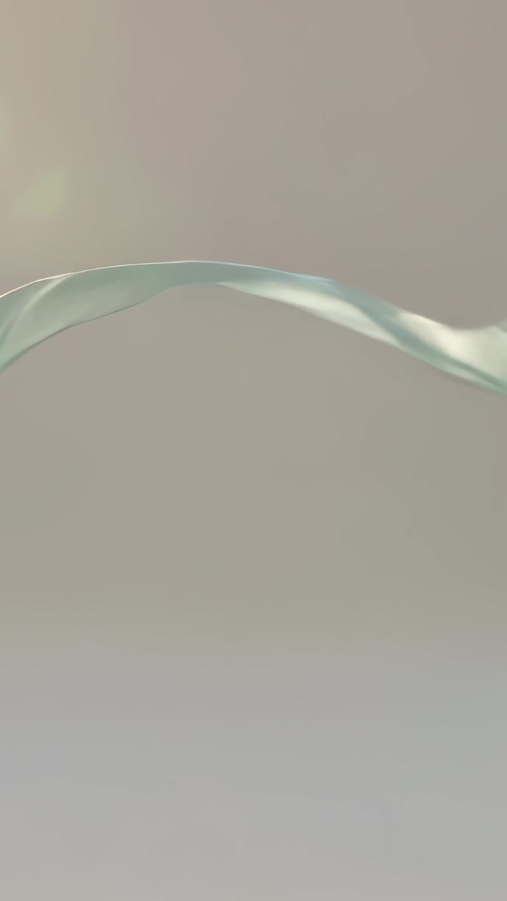 Vertical video: Upper-left flare causing silk ribbon curling, flattening, drifting across gray wall