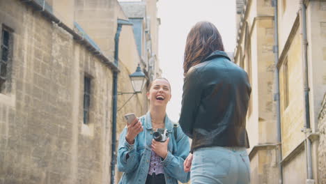 pareja de mujeres del mismo sexo tomando fotos la una de la otra en una cámara digital retro alrededor de oxford, reino unido juntos.