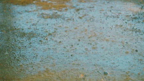 close up slow motion shot of rain drops falling on a muddy, dirty road in curacao