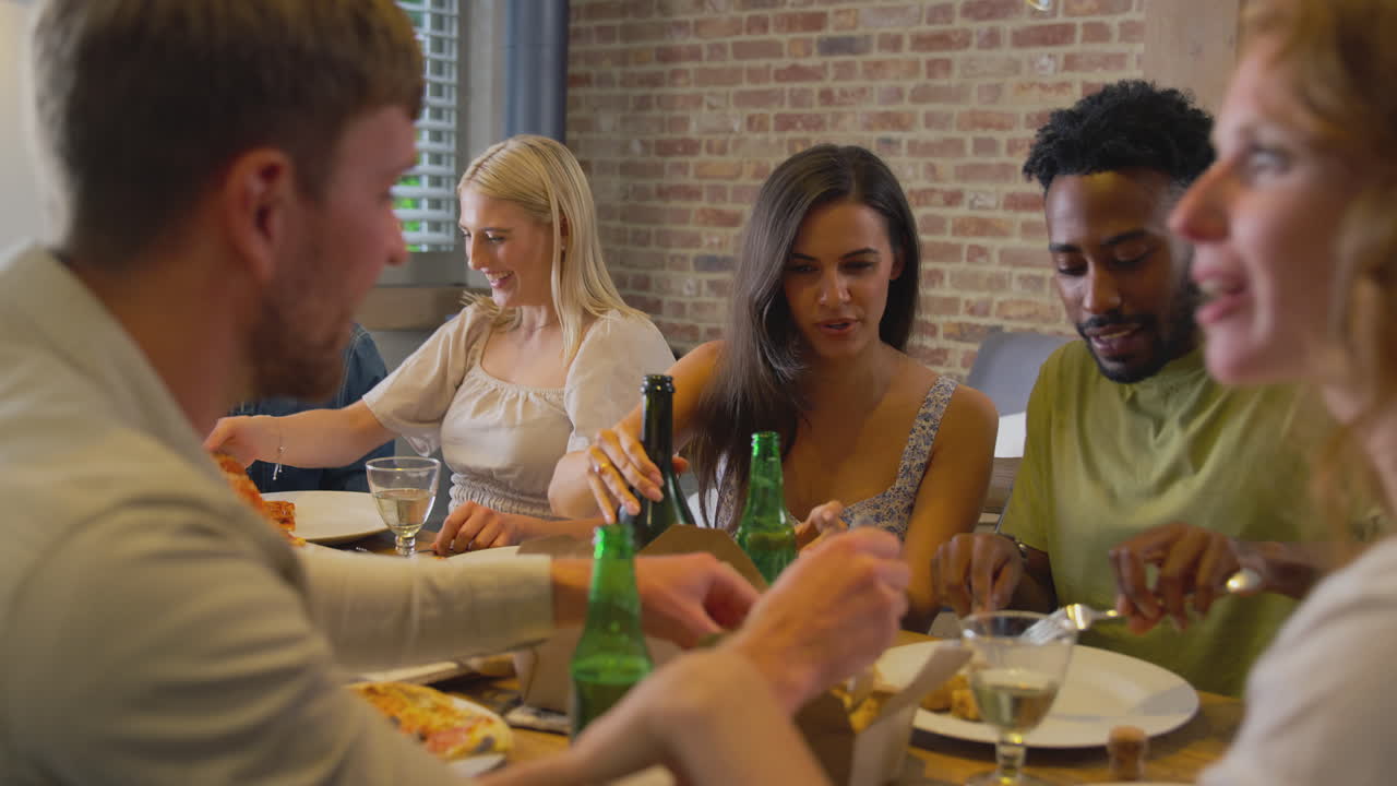 Multi-Cultural Group Of Friends Enjoying Beer And Pizza Party At Home Together