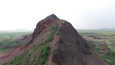 hintere luftaufnahme eines paares, das auf einem berg wandert, mit blick auf eine weite wiese