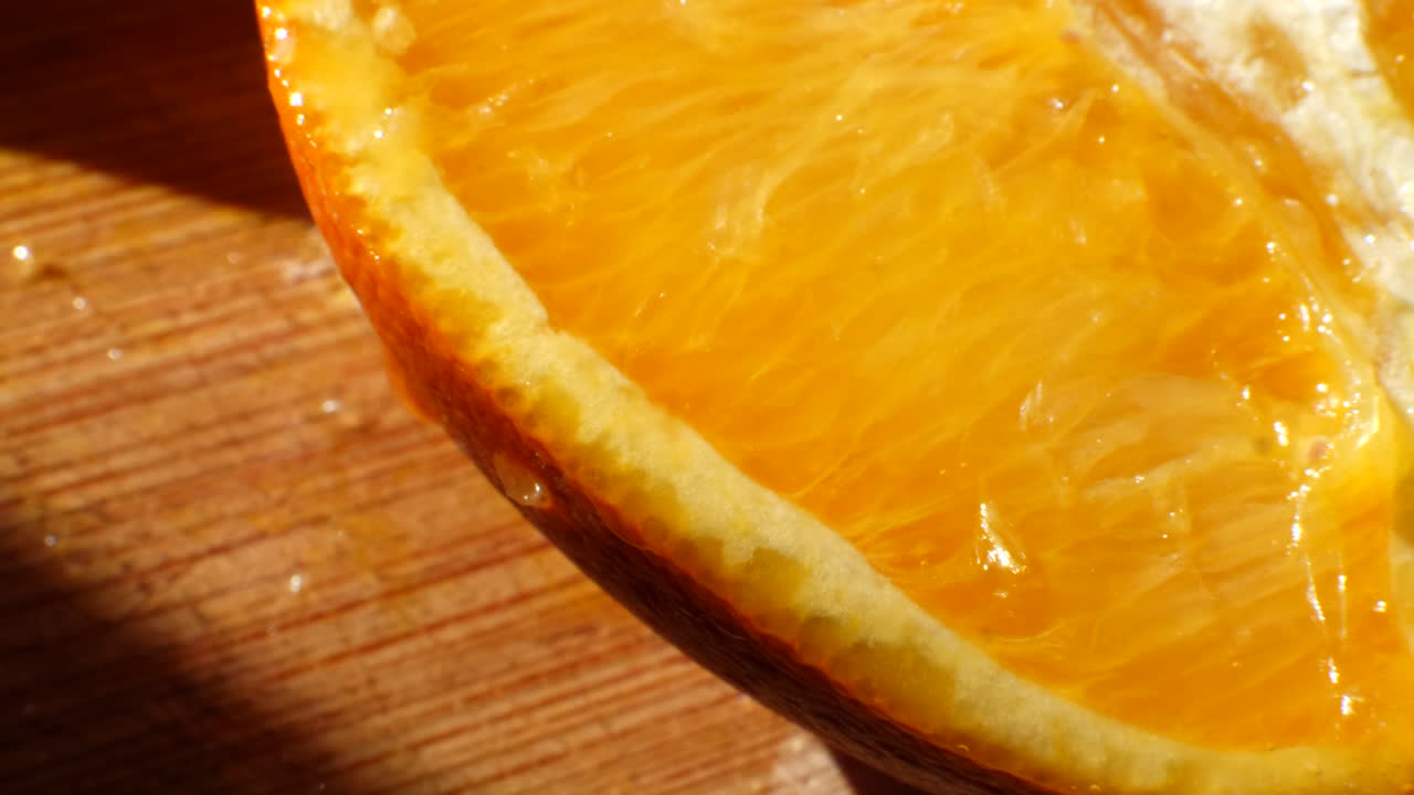 foto macro en una rodaja de fruta naranja madura con jugo goteando a la luz del sol en una tabla de cortar para un refrigerio saludable