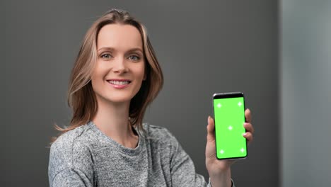dama alegre demuestran teléfono móvil pantalla verde clave de croma teléfono inteligente. cámara roja dragón 4k