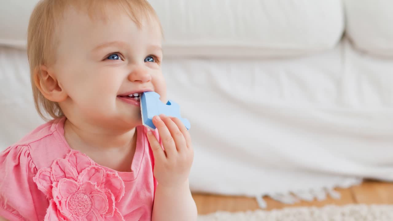 animación de un bebé caucásico sonriente sosteniendo una pieza azul de rompecabezas