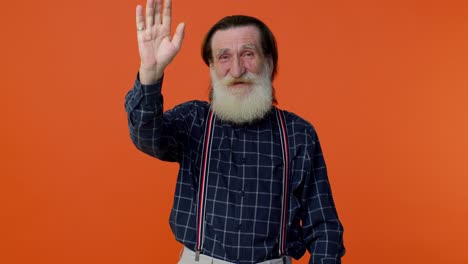 Happy-friendly-elderly-man-waves-hand-palm-in-hello-gesture-welcomes-someone-positive-emotions