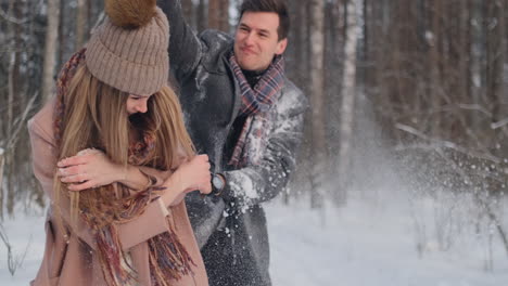 una pareja feliz está jugando juegos de invierno afuera disfrutando de la luz del sol y del cálido clima invernal en las montañas. un chico fuerte lleva a su novia sobre sus hombros y la hace girar.