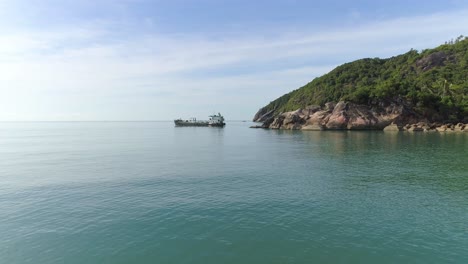 a cargo ship sails past a rocky island in the ocean
