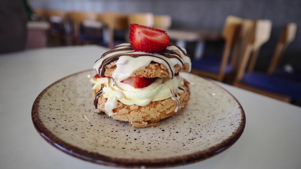 Delizioso dessert di pasta choux con panna, fragole e glassa al cioccolato