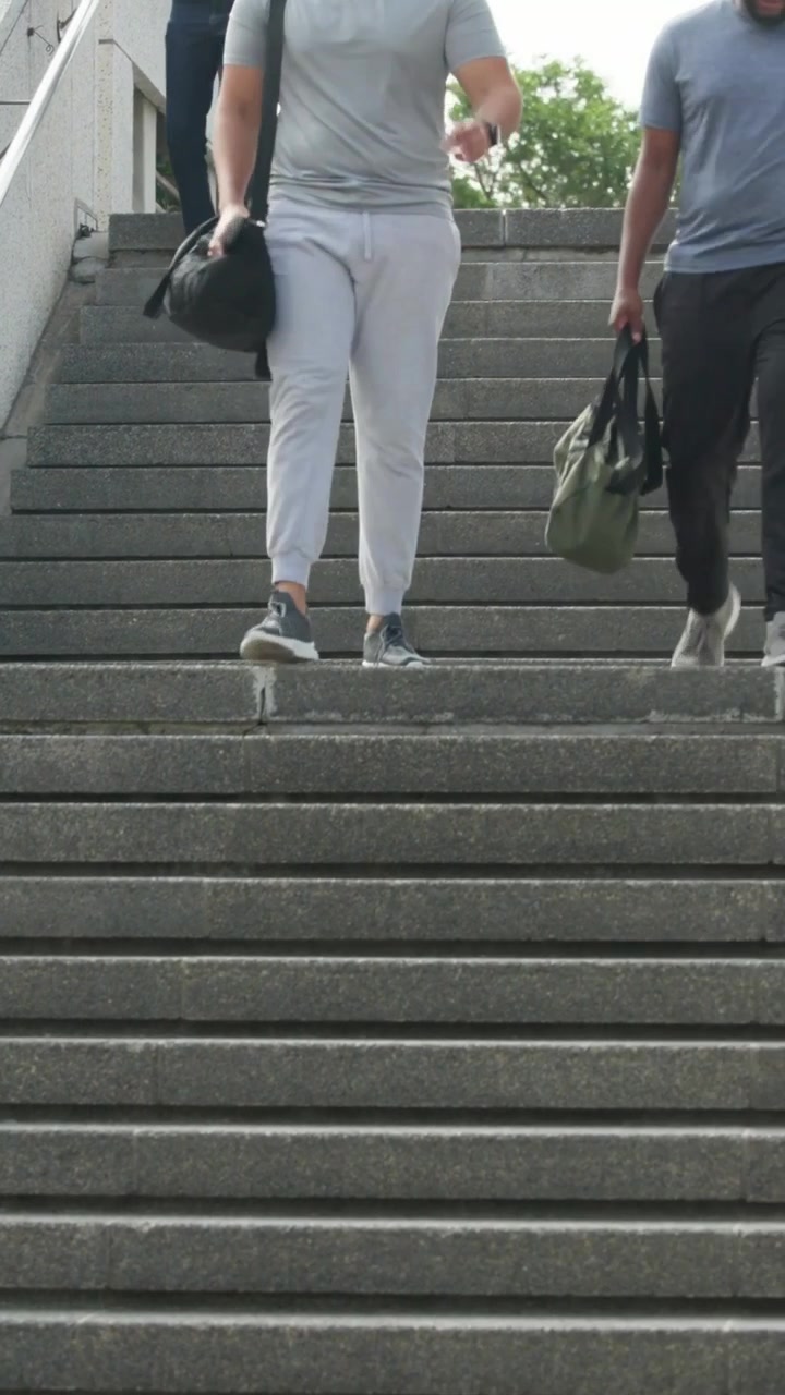 Vertical video: Panning cam tailing blurred woman with cup revealing stairway during commute