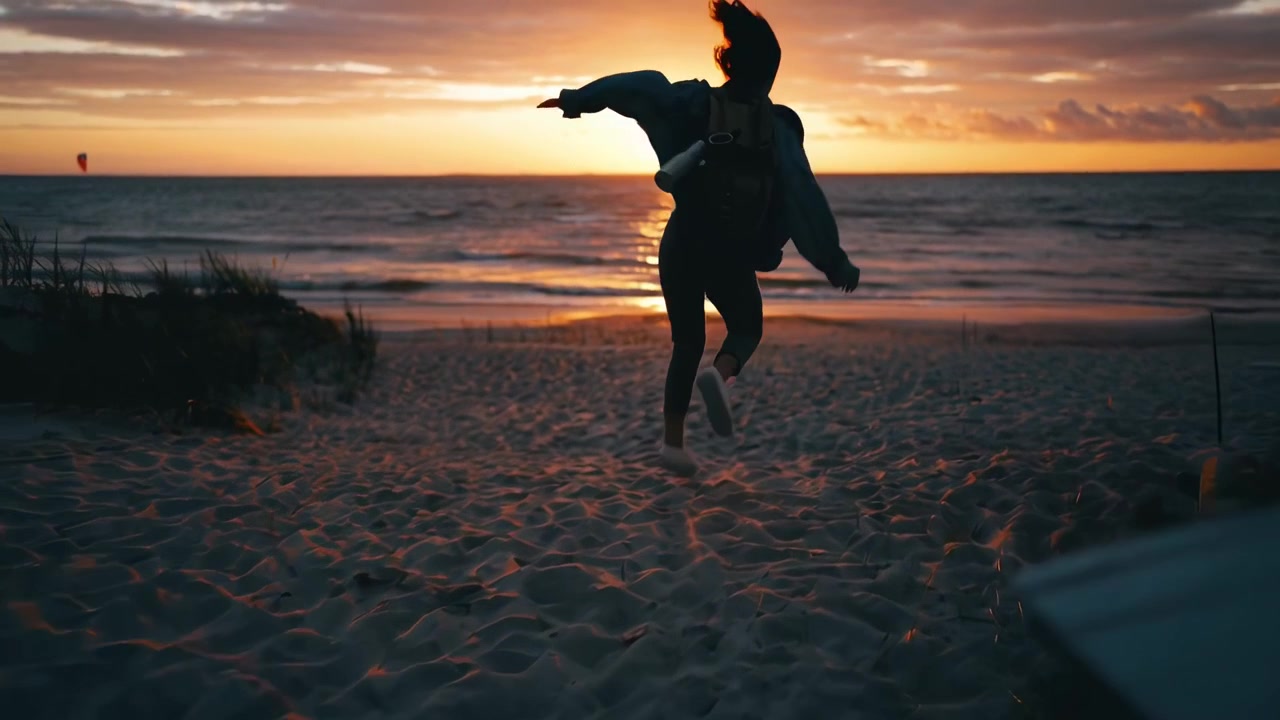 Giovane donna con zaino che corre verso l'oceano al tramonto