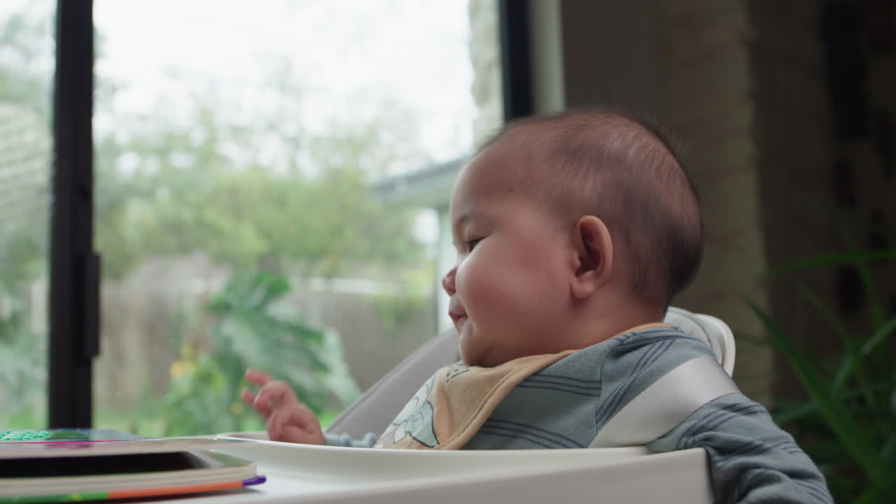 귀여운 아기가 웃고 미소 짓고 높은 의자에 앉아 있습니다.