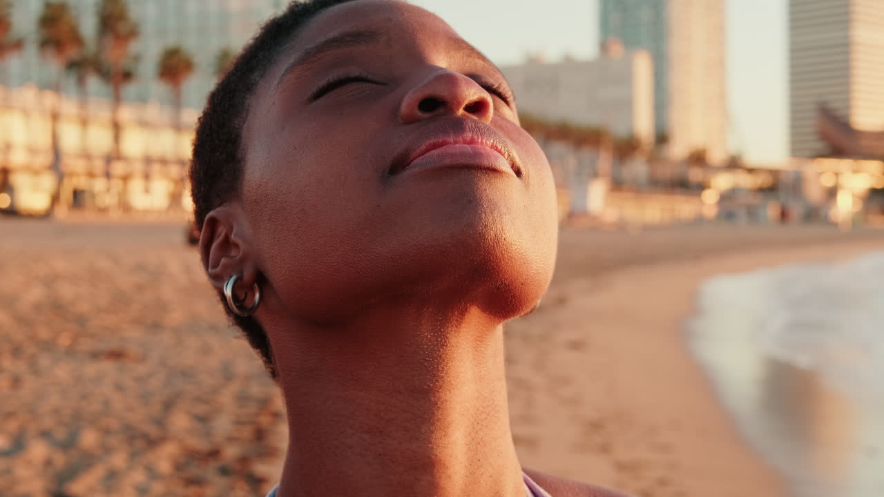 Jeune femme afro-américaine sereine profitant du lever du soleil sur la plage