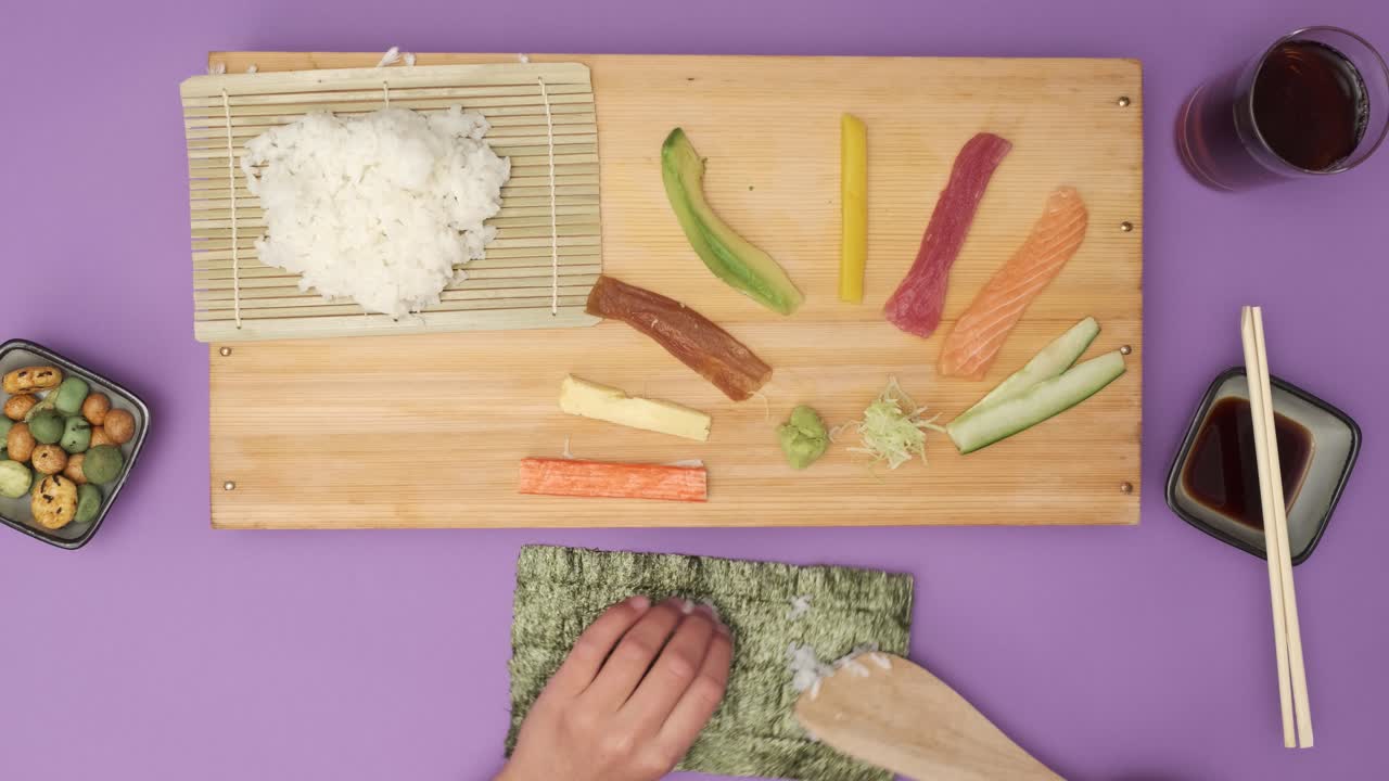 top shot de dos manos preparando sushi en la mesa violeta