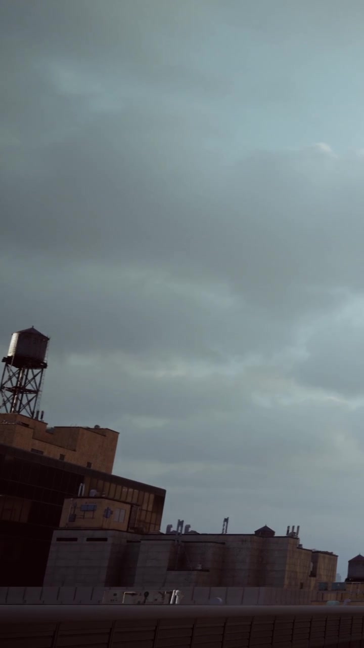 Cielo nuvoloso sopra un edificio cittadino con una torre dell'acqua in vista nel pomeriggio.
