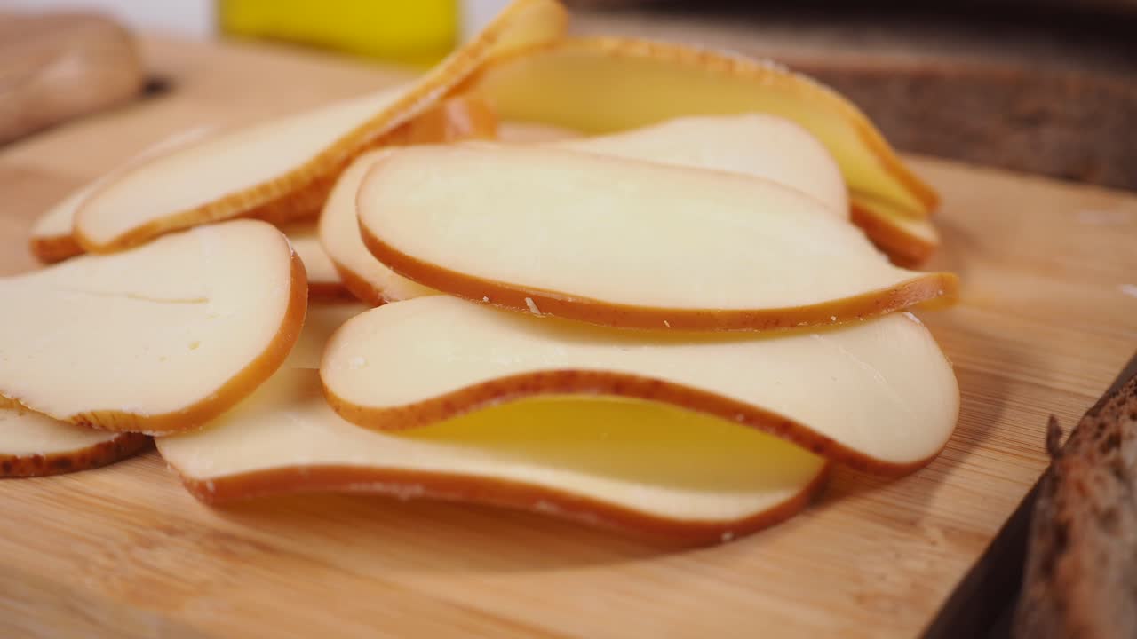 Close-up de queijo fatiado em uma tábua de corte de madeira.