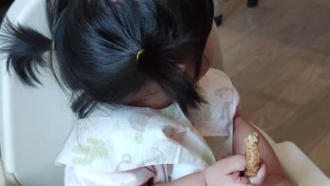 Asian-Cute-Baby-Girl-Eating-Her-Homemade-Food-On-Baby-Feeding-Chair