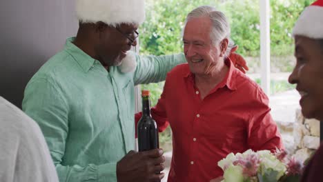 Happy-group-of-diverse-senior-friends-welcoming-in-doorway-at-christmas-time