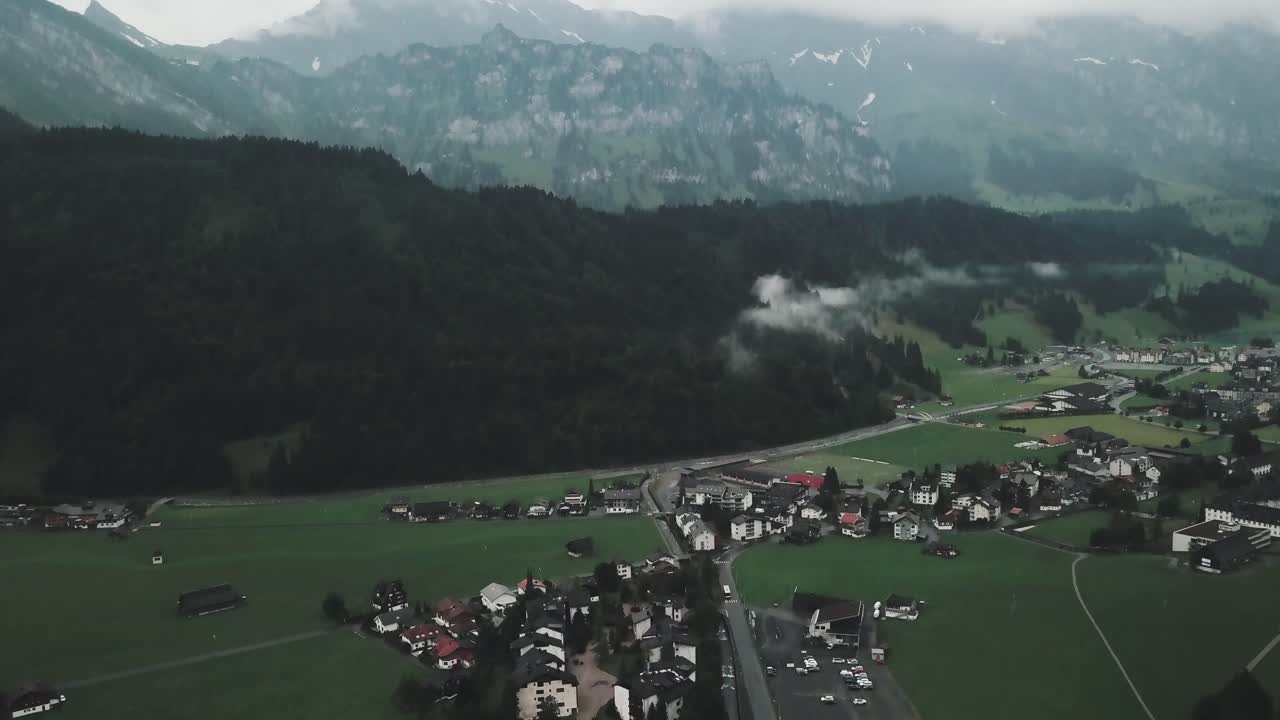 dron aéreo panorámico lento sobre la pequeña ciudad suiza de endelberg para mostrar grandes cadenas montañosas en un día nublado