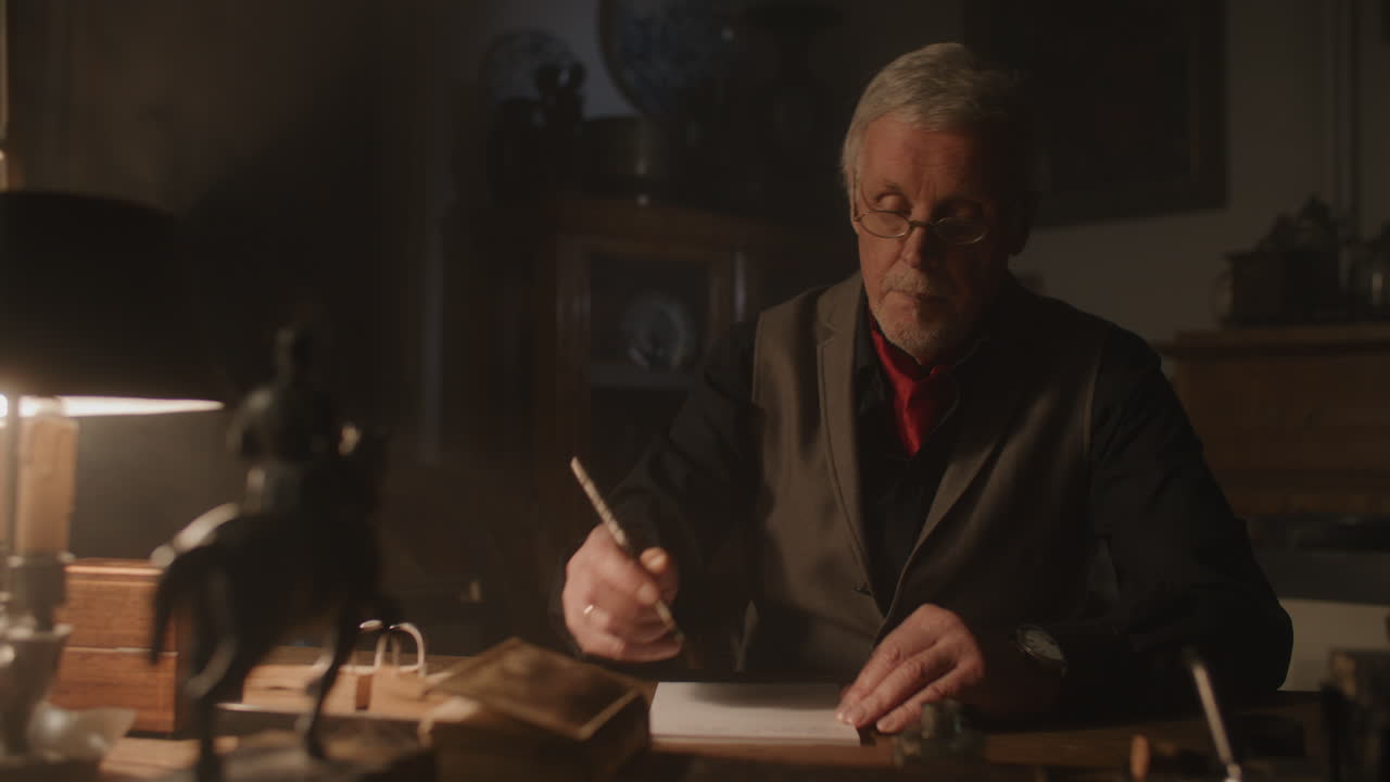 Old passionate man writes a letter in his office at night