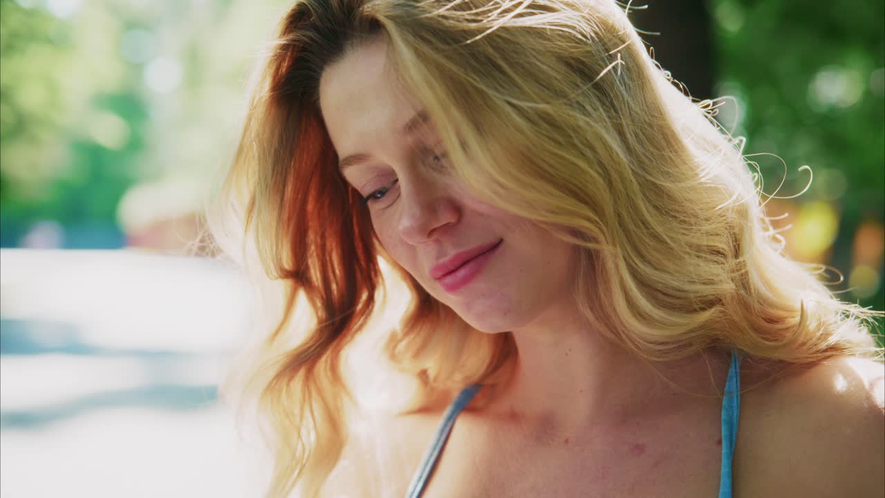 Young Blonde Woman Looking Down Thoughtfully in Sunlight